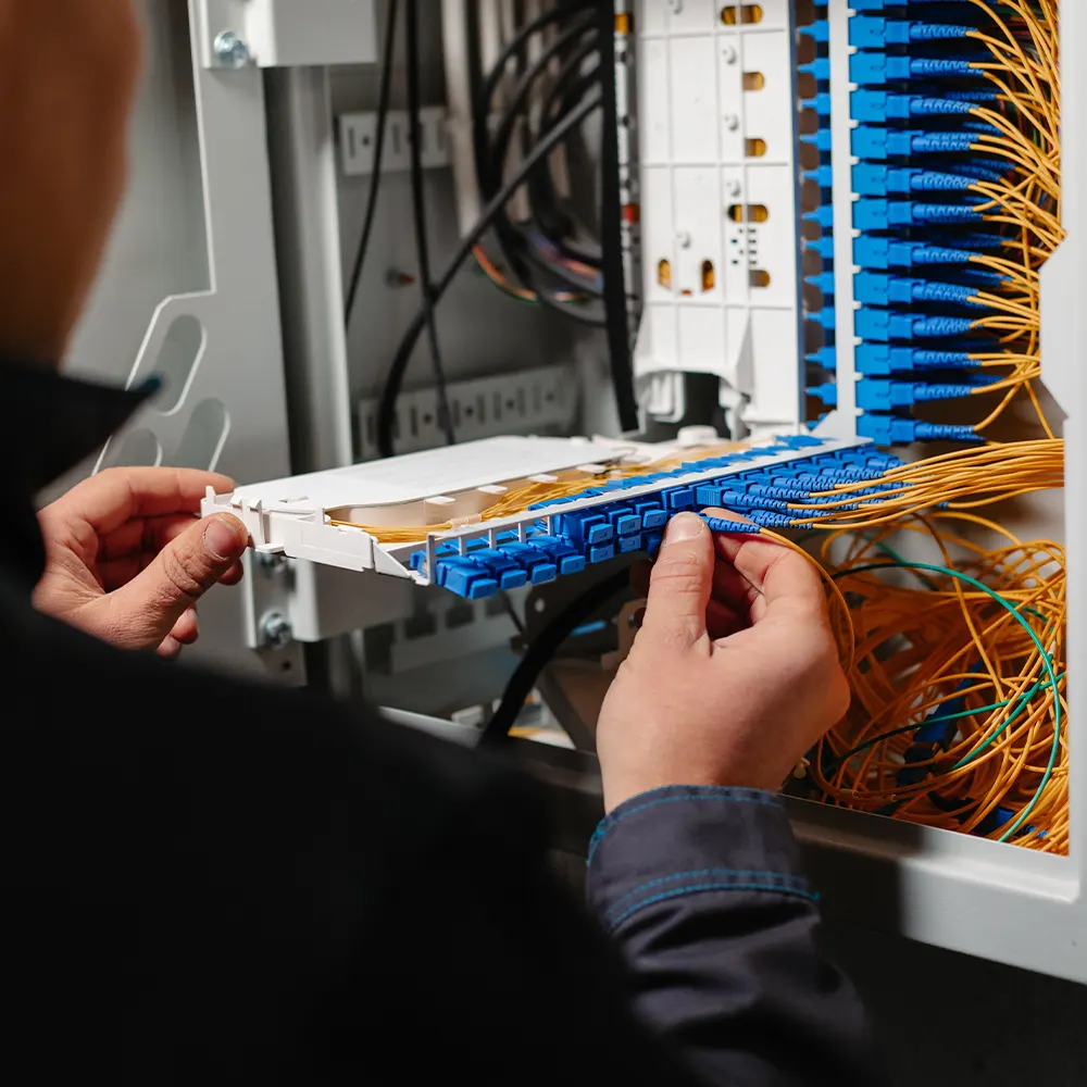Technician terminating fiber optic cables in a patch panel